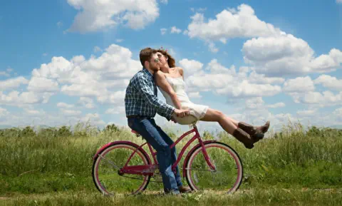 Glückliches Ehepaar fährt zusammen auf einem Fahrrad und schwört auf das Liebes Rezept